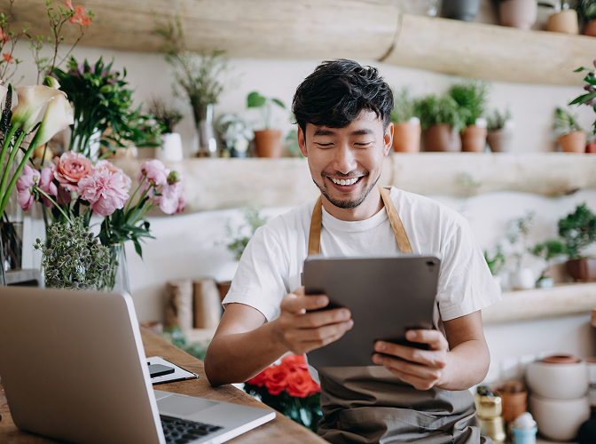 A flower shop owner looking at his tablet while at work.