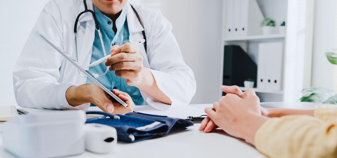 Close-up of a doctor showing a patient something on a tablet.