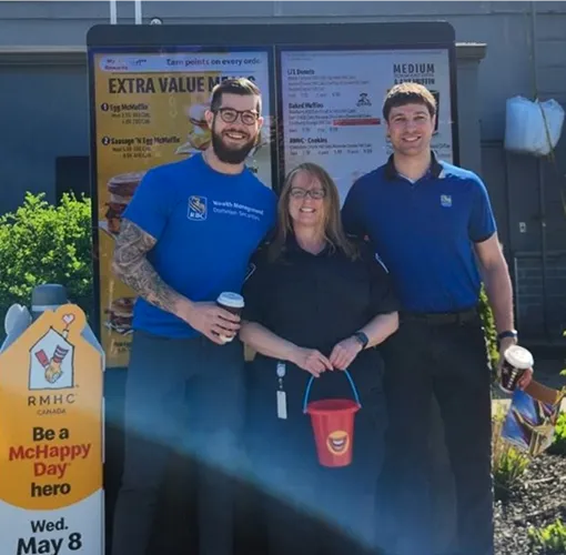 Three volunteers standing in front of a McDonald's drive thru sign.