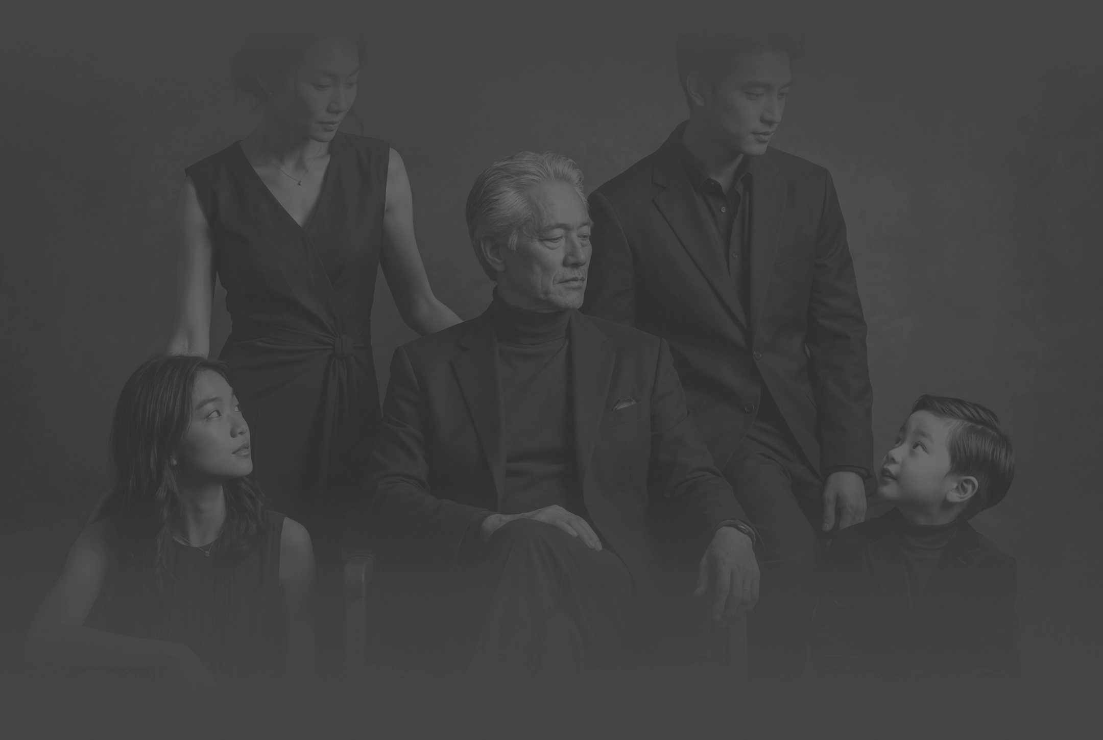 A black and white photo of a family with the father seated and his wife and children around him.