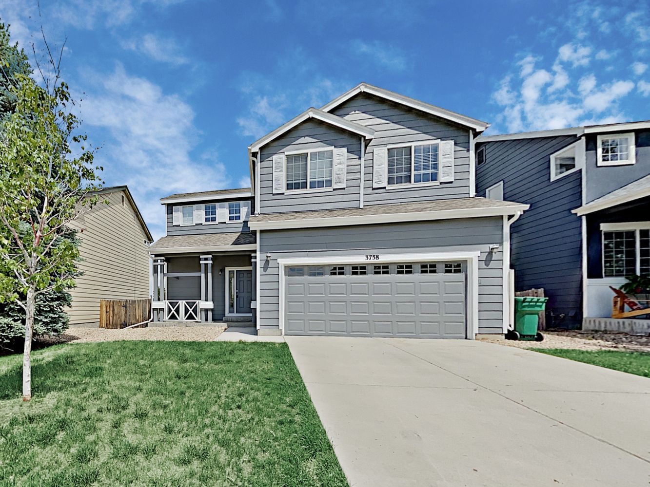 Gorgeous front of home shot featuring covered porch and attached two-car garage at Invitation Homes Denver.