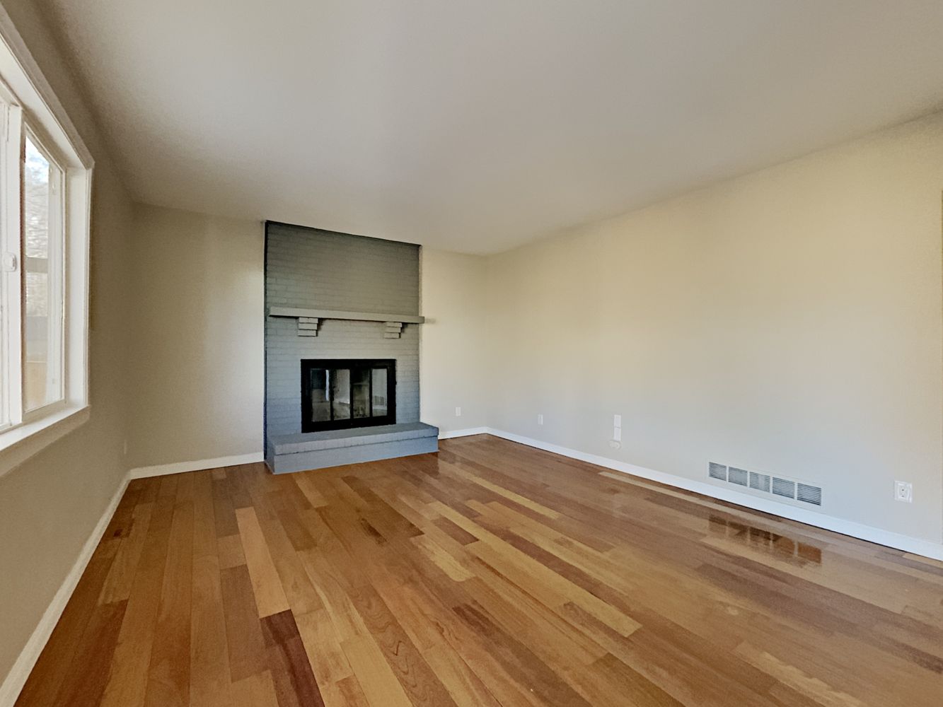 Living room with fireplace and wood-style flooring at Invitation Homes Denver.