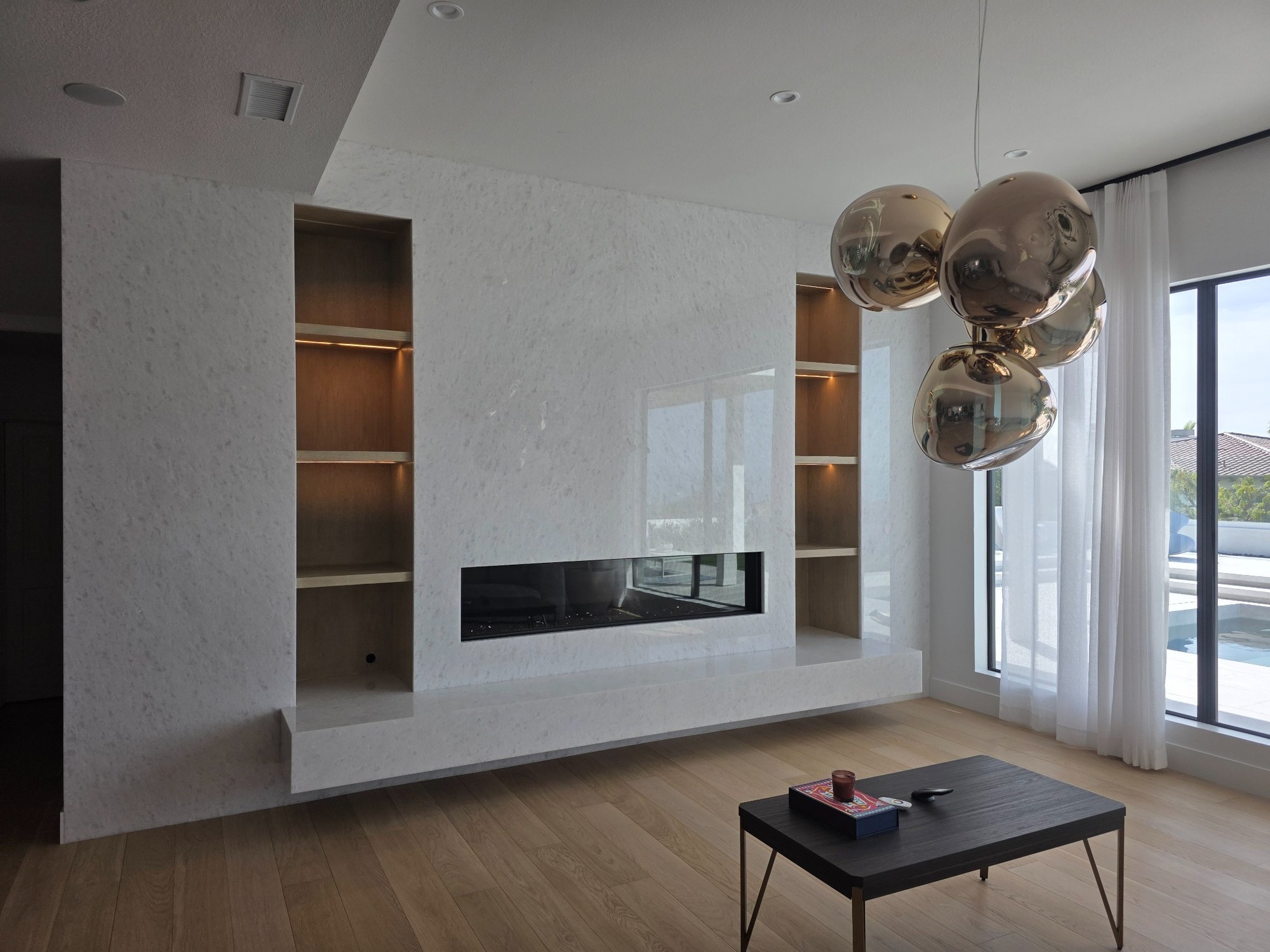 Custom living-room feature wall with built-in shelving, fireplace, and clean modern finishes. 