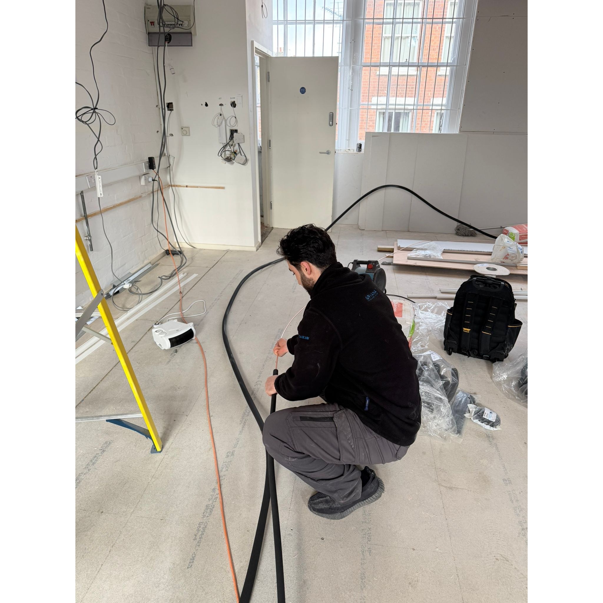 Airvana engineer running refrigerant pipework through a new office fit-out in London before the units go in.