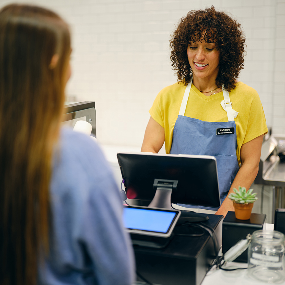 A woman in an apron interacting with a customer.
