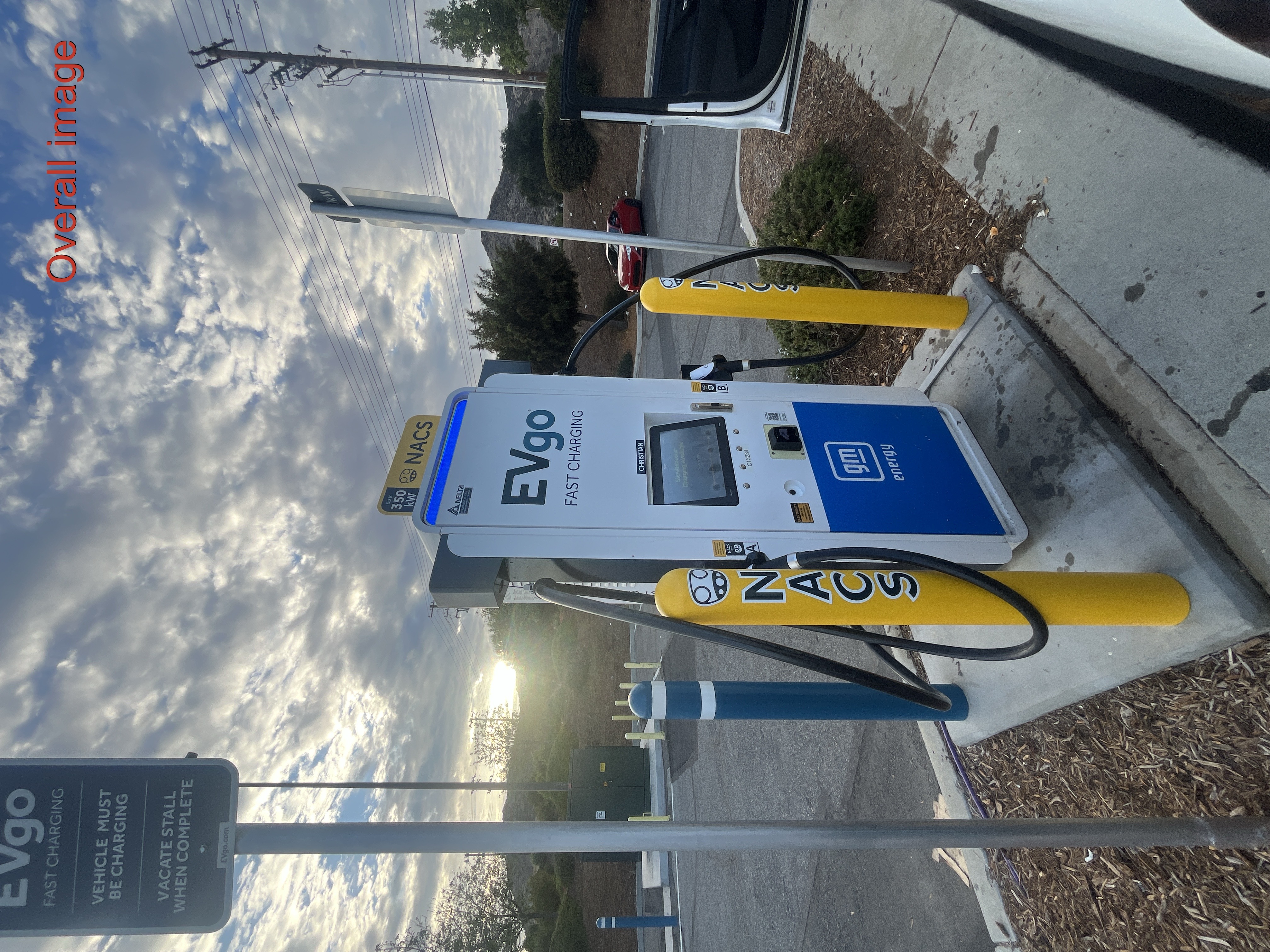 NACS EVgo fast charging unit installed in marked parking space at a public charging station, with EV 