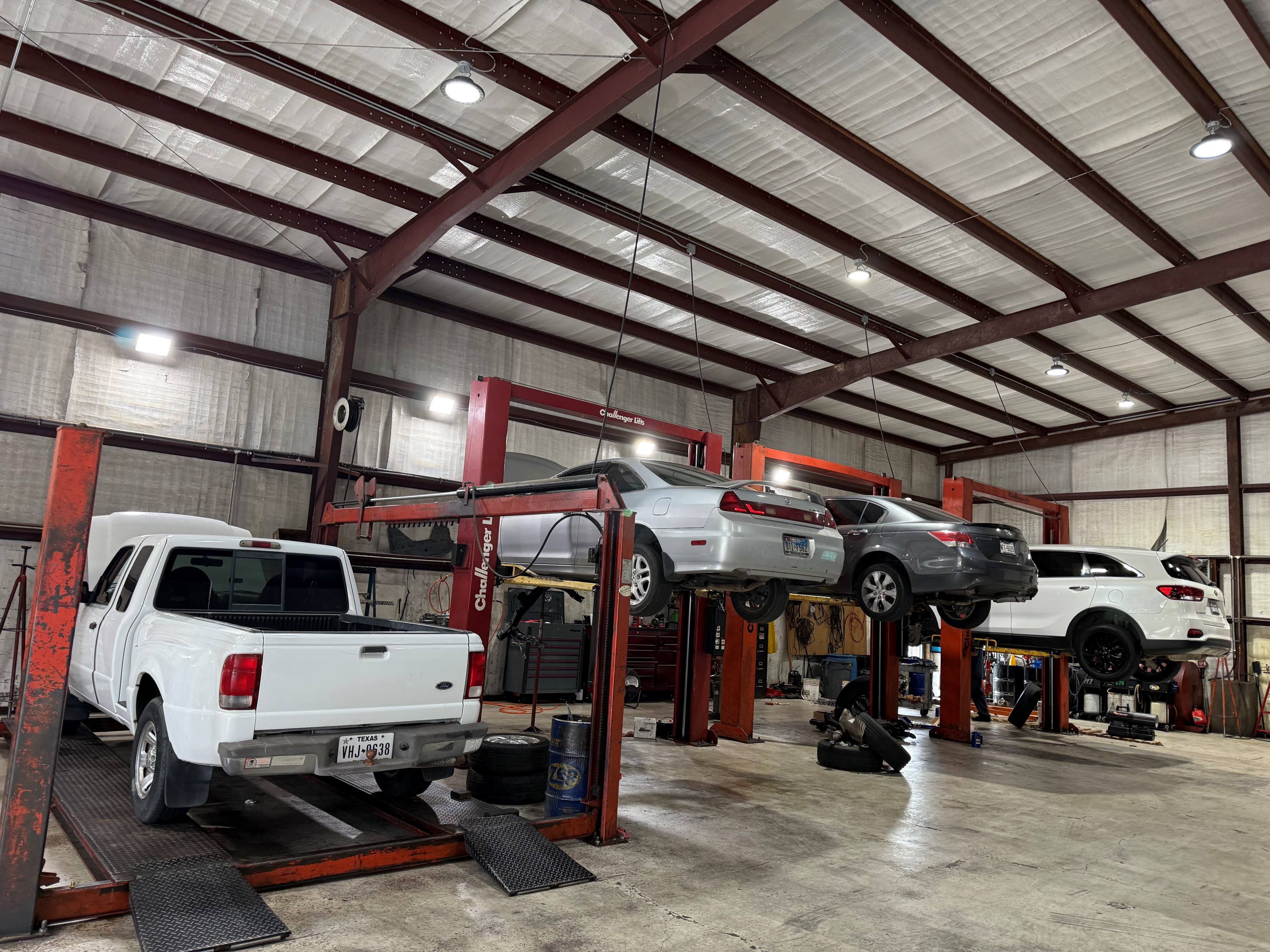 Interior view of the Yes! Automotive auto repair shop in Porter, TX, featuring multiple service bays, professional vehicle lifts, and vehicles undergoing automotive maintenance and repair.