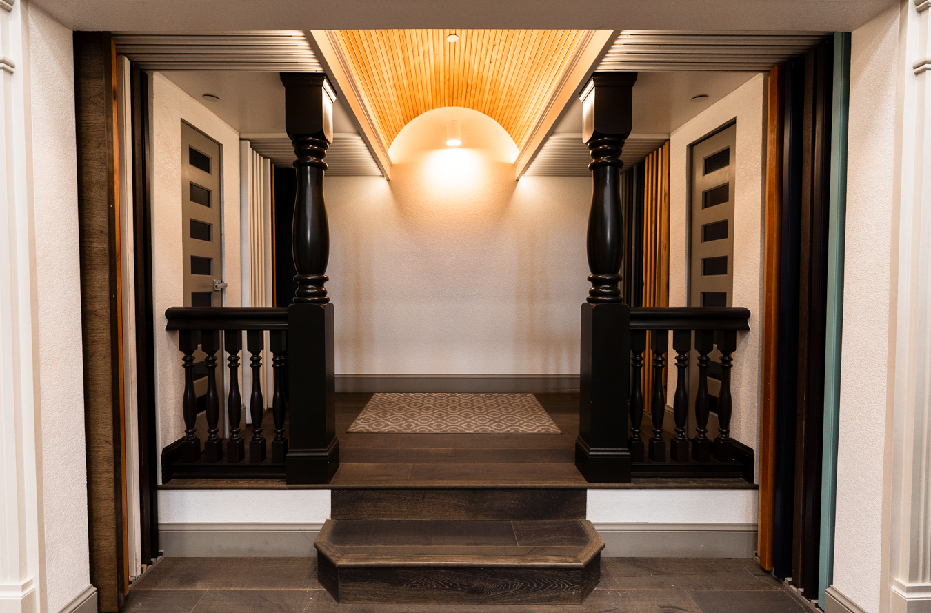 Elegant hallway with dark wood columns, modern doors, and warm lighting, showcasing Builders FirstSource craftsmanship.