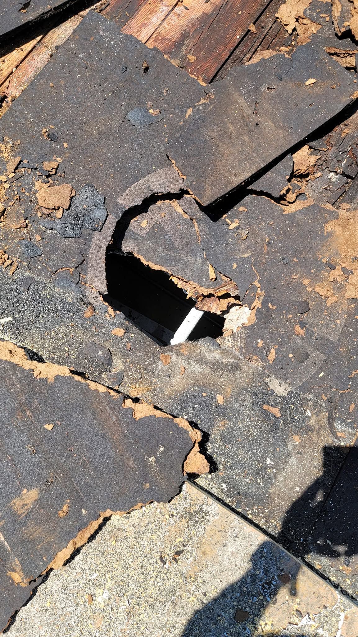 Severely deteriorated roofing materials exposing damaged wooden roof decking and structural componen 