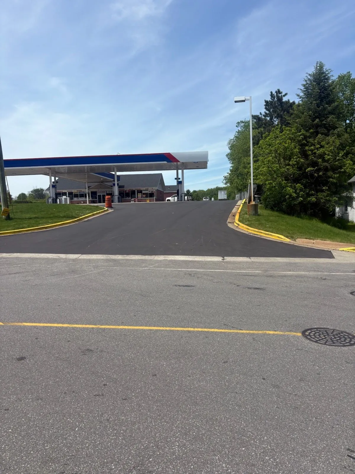 Freshly paved asphalt entrance and parking access area serving a commercial gas station with smooth, durable blacktop surface.