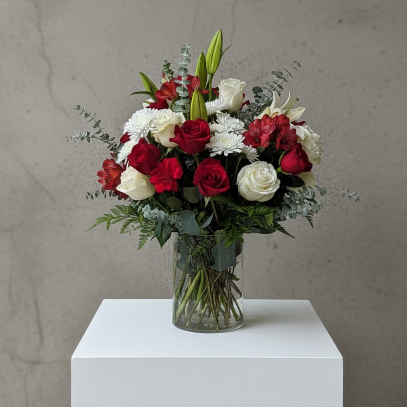 A timeless blend of rich red and soft ivory blooms, thoughtfully arranged in a clear glass vase. Featuring premium roses, seasonal accent florals, and fresh eucalyptus, this design captures elegance, warmth, and heartfelt sentiment. Perfect for celebrating love, honoring meaningful moments, or simply brightening someone’s day.