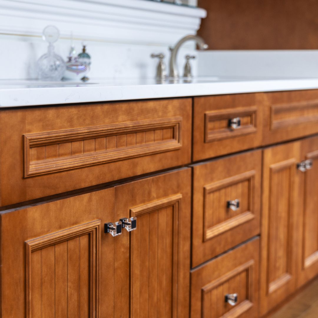 Close-up of rich wood cabinetry with a white quartz countertop and brushed nickel fixtures.