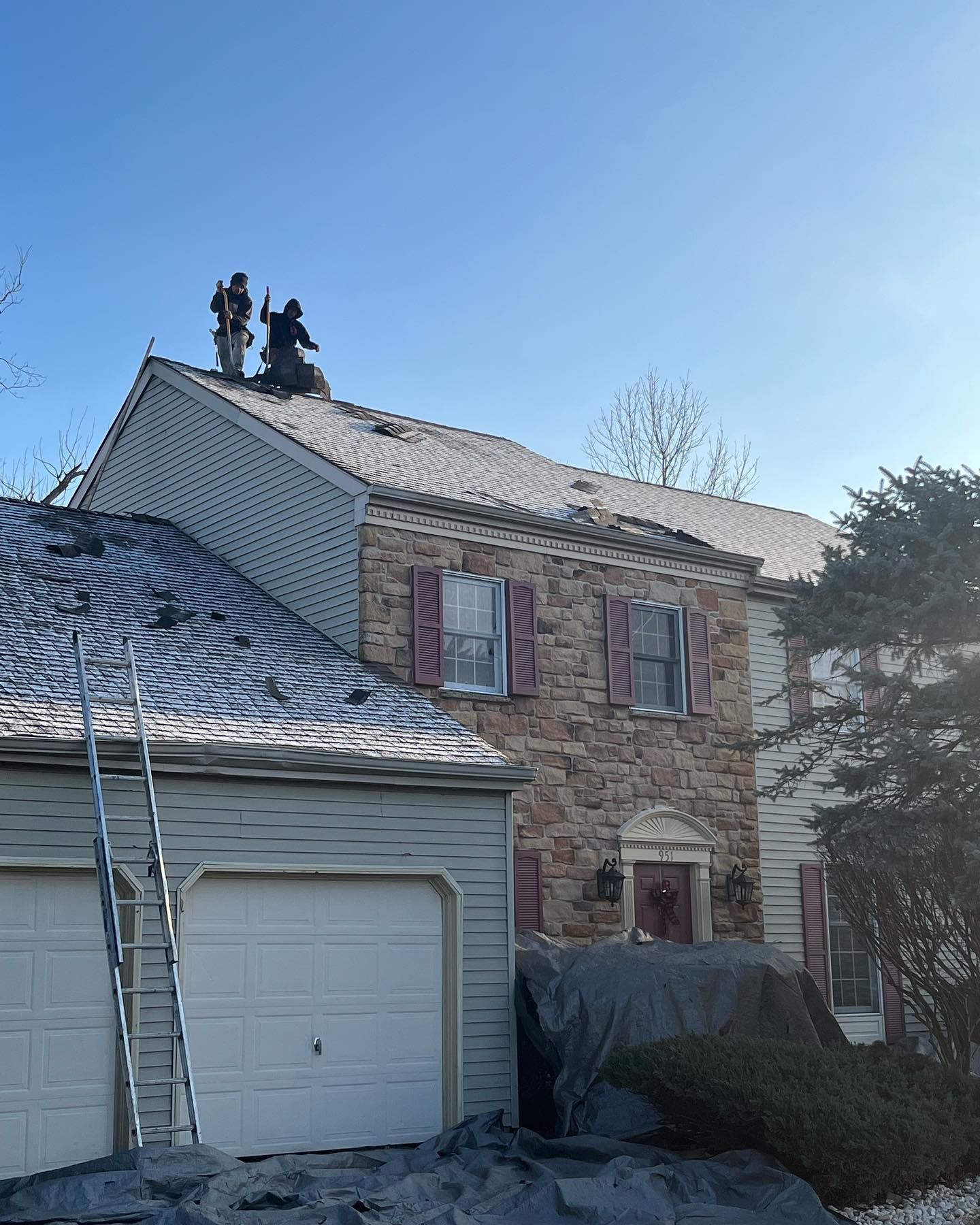 Roofing professionals remove damaged shingles and prepare a residential roof for replacement. Skille 