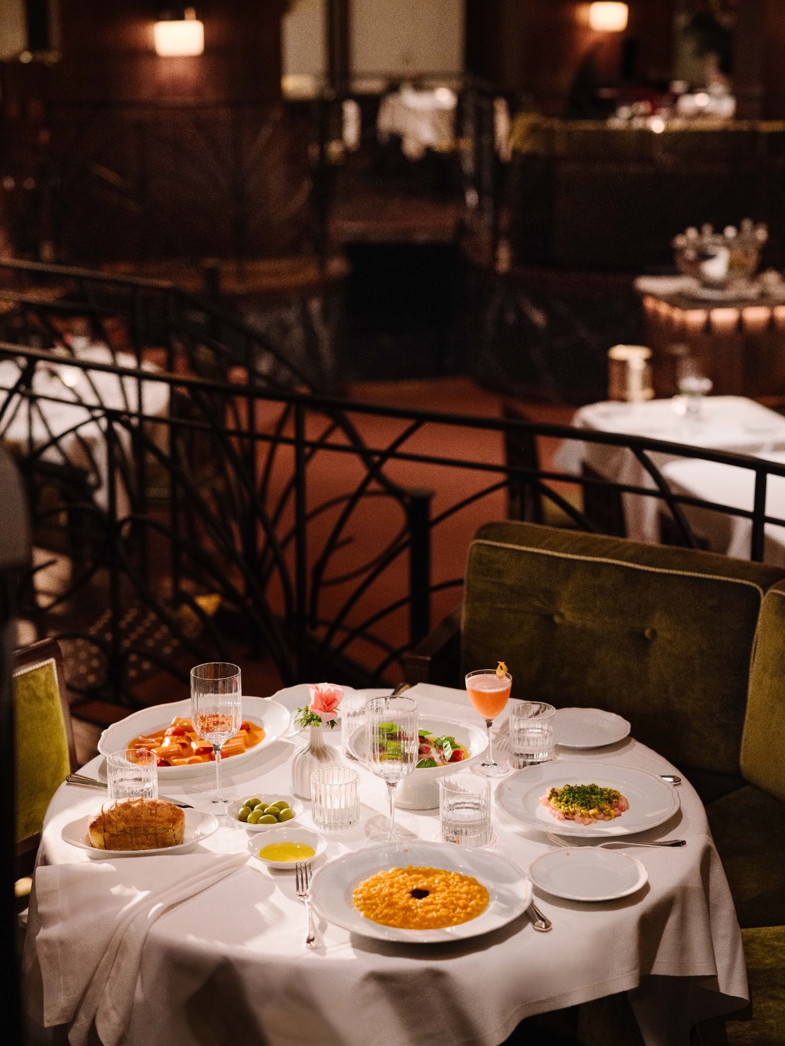 Elegant restaurant table set with Italian dishes, wine glasses, and candles in a softly lit dining room.