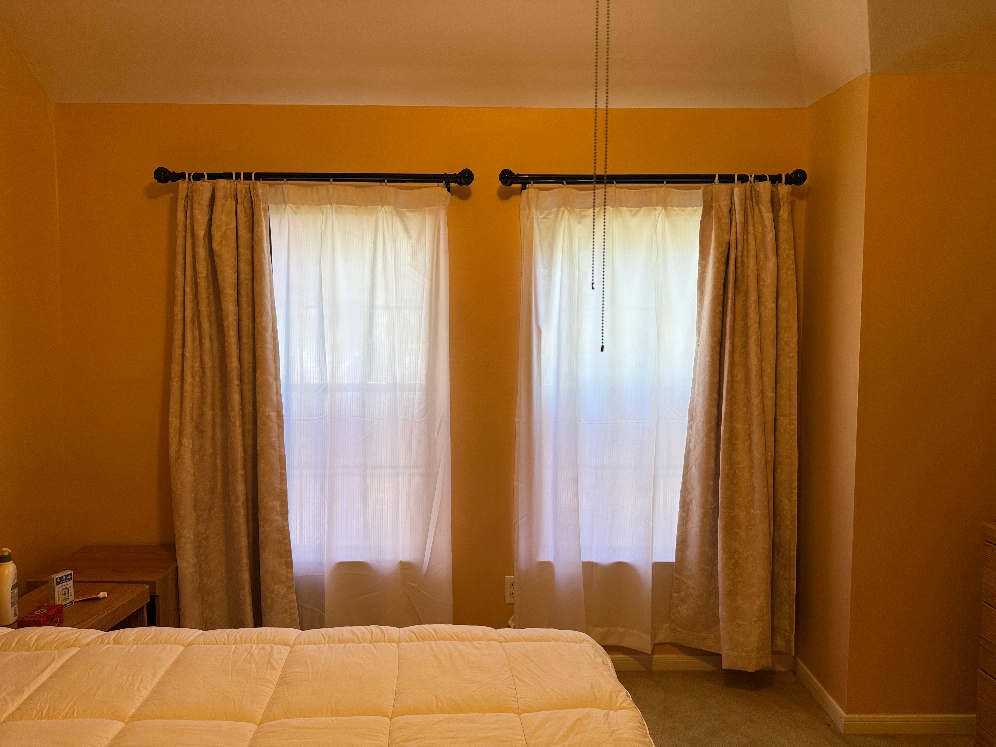 Curtains installed over two bedroom windows in a residential home.