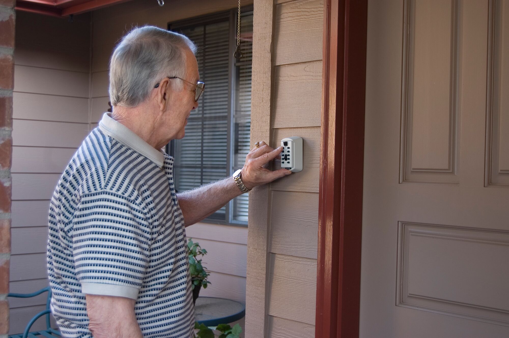 Image of a person putting in a combination code into a locked key safe.