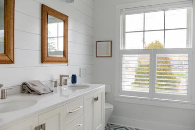 We absolutely adore how these white shutters brighten this bathroom! In spaces like bathrooms and kitchens, where natural light is essential but privacy remains a concern, cafe shutters are a perfect choice.