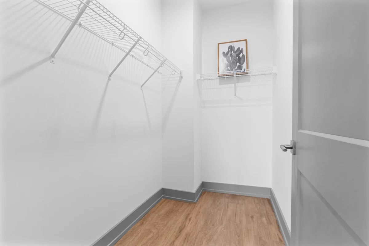 A white hallway with a wooden floor and a white door. 