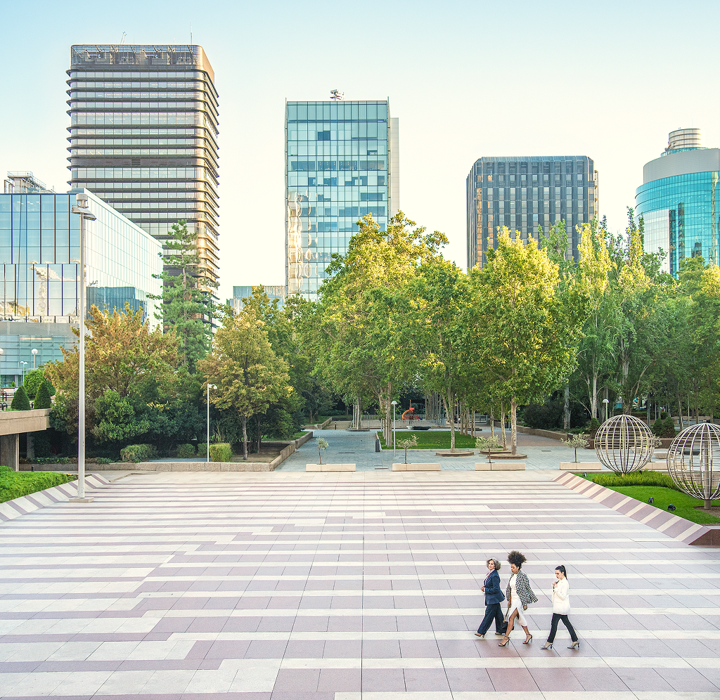Three colleagues strolling through a courtyard in the city.