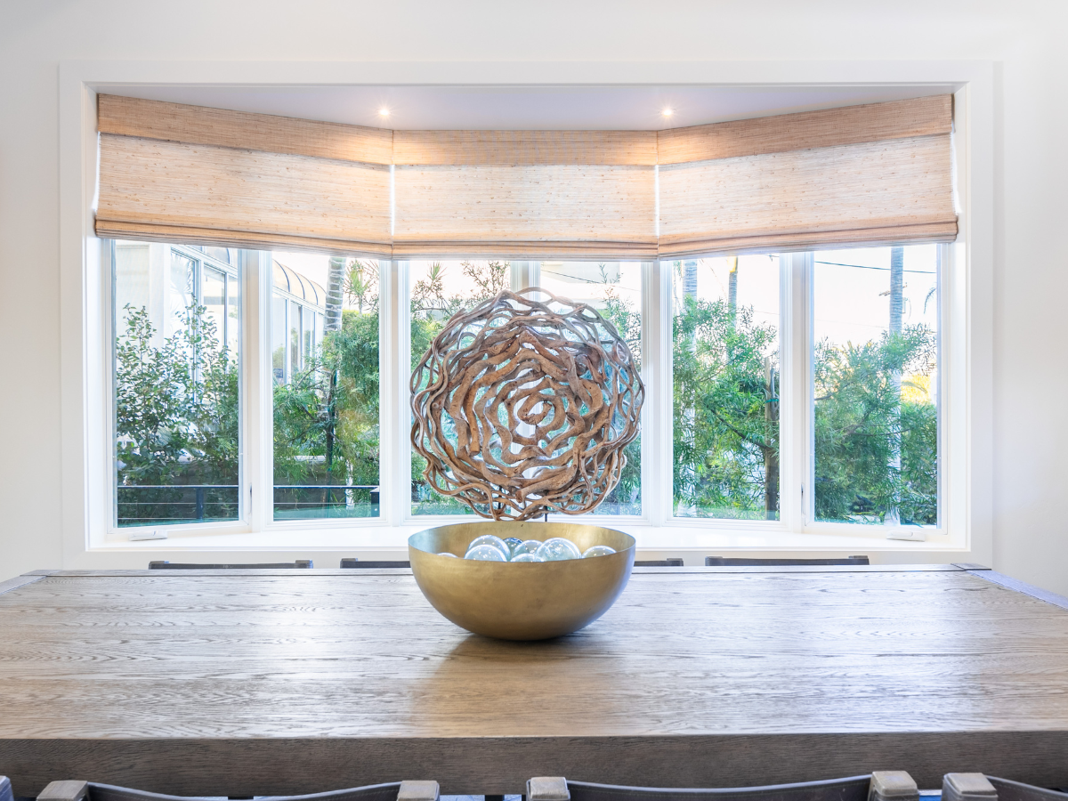 Woven wood shades add warmth and texture while softly filtering light, creating a relaxed, natural feel.