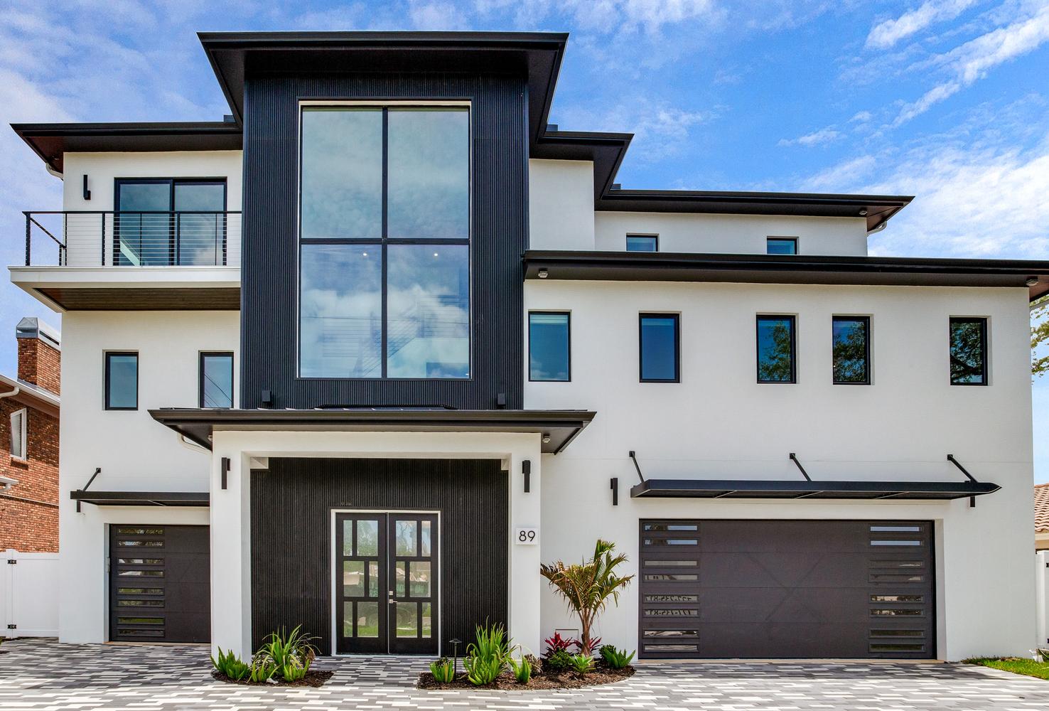 Modern AVENTIS custom home exterior featuring a luxury multi-story coastal design, clean architectural lines, large windows, and a spacious driveway.