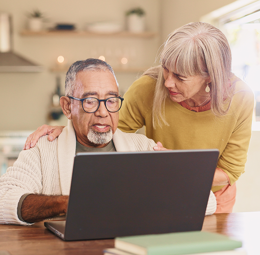 An elderly couple looking at a laptop.