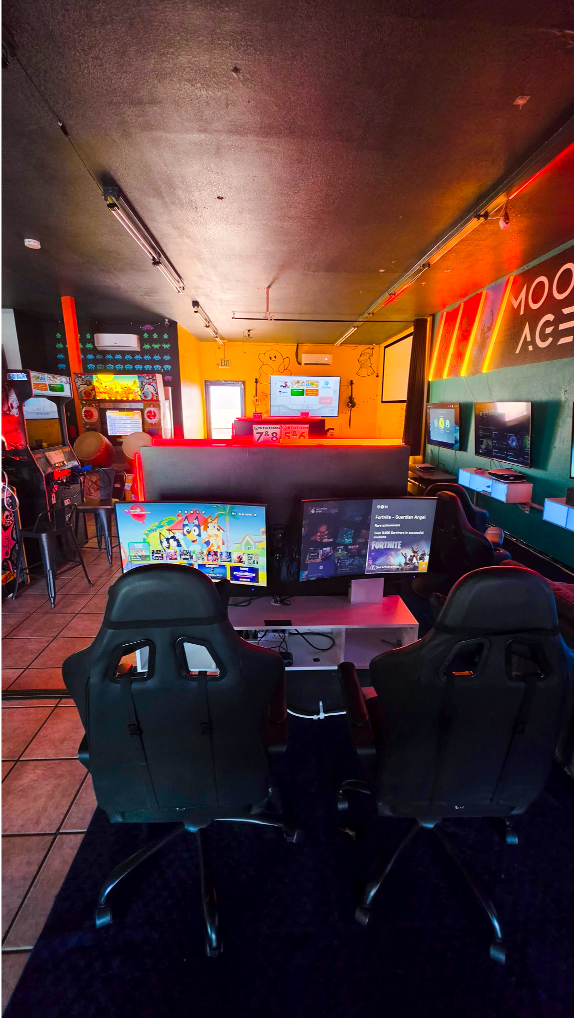 Play together at MoonAge’s console gaming lounge, featuring multiple gaming stations, comfortable se 