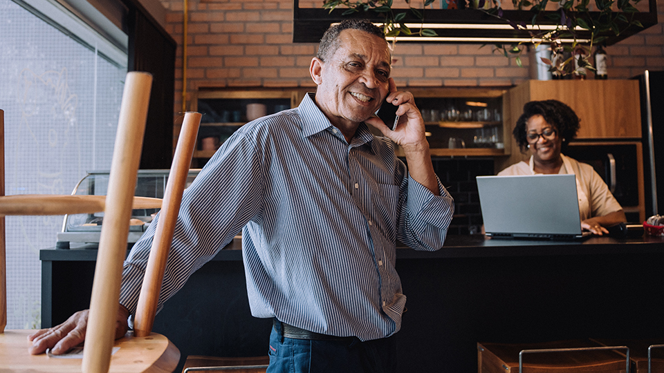 A man talking on the phone and a woman using a laptop