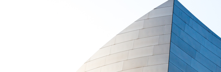 Pointed tip of a glass-faced skyscraper against a clear sky.