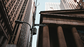 Upward view of the New York financial district including a sign for Wall Street.