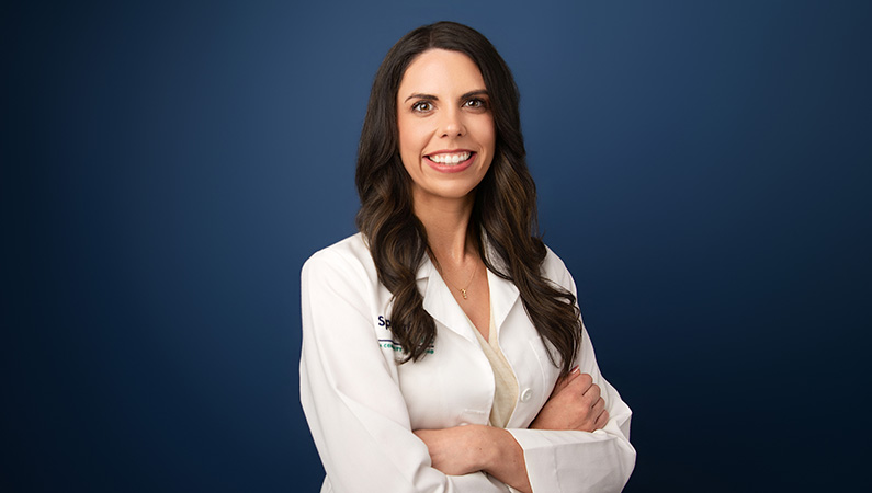 Female wearing white medical coat in front of blue background