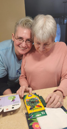 Caregiver supporting an older adult with meaningful activities and companionship at home.