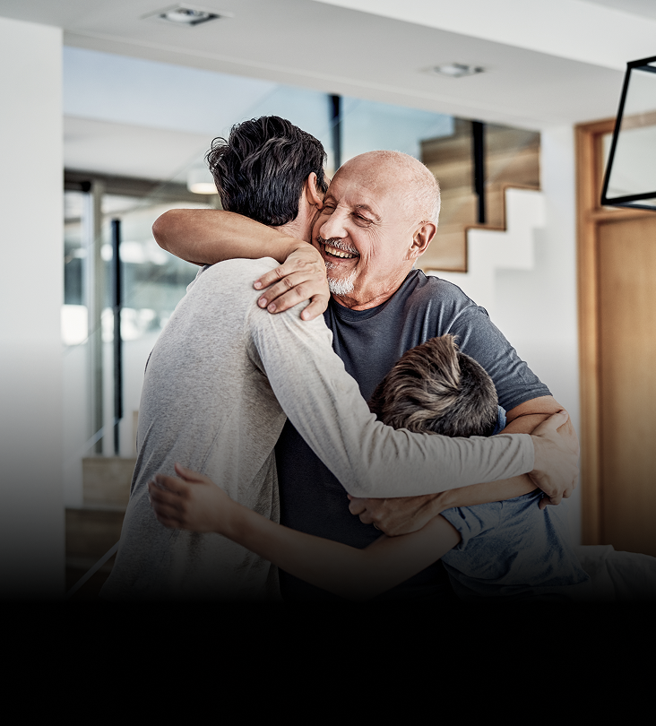A grandfather hugging his son and grandson.