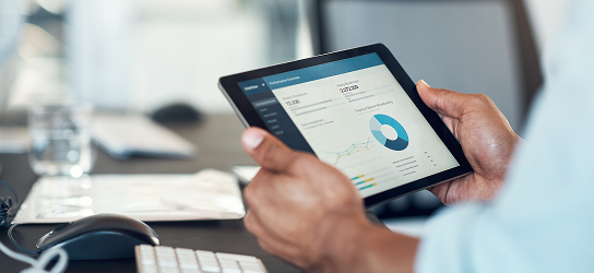 Close-up of a professional viewing charts and graphs on a tablet.