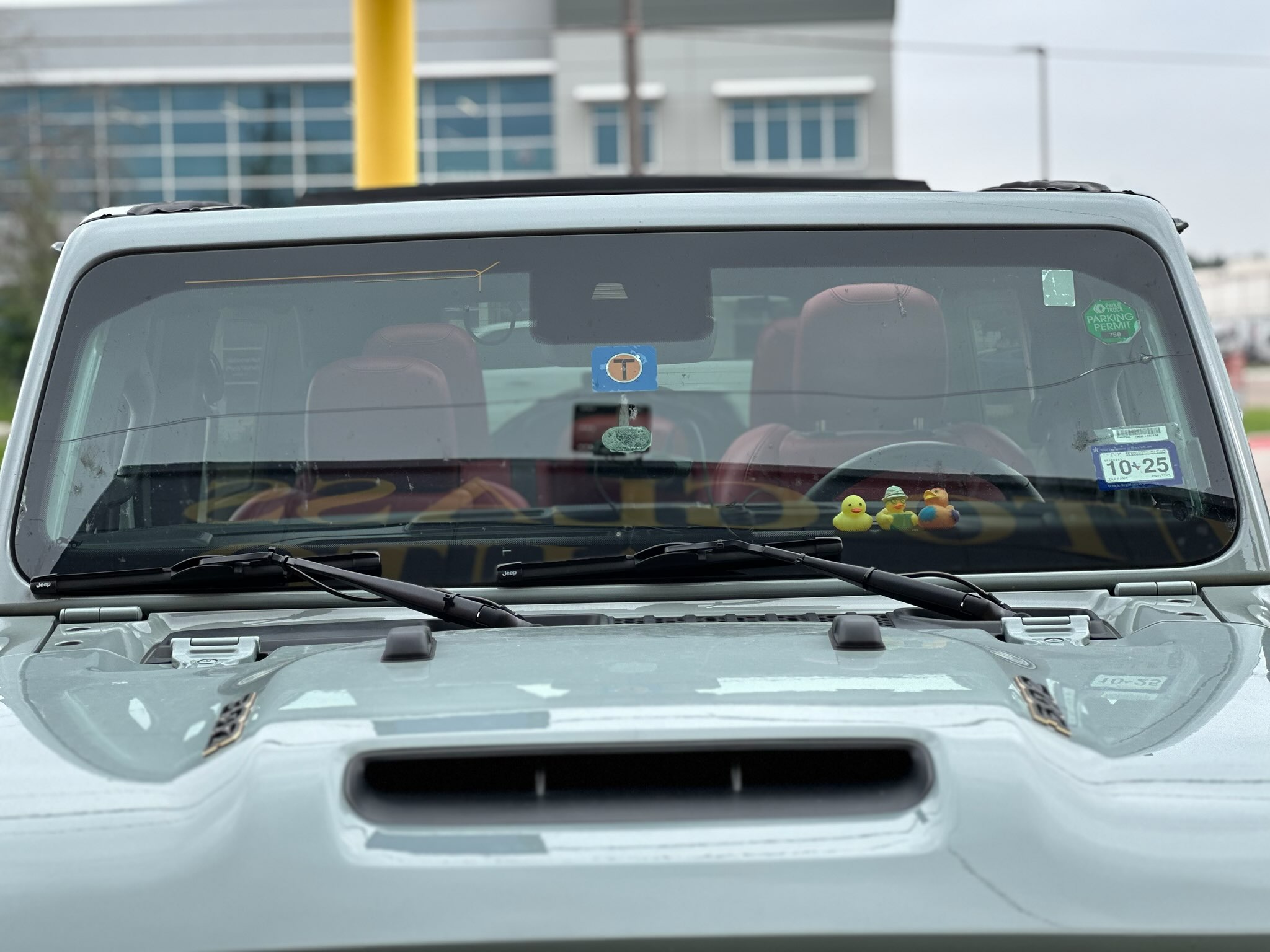 Close-up of the front windshield on a Jeep following auto glass service. The glass, wipers, dashboard, and vehicle interior are visible through the windshield.