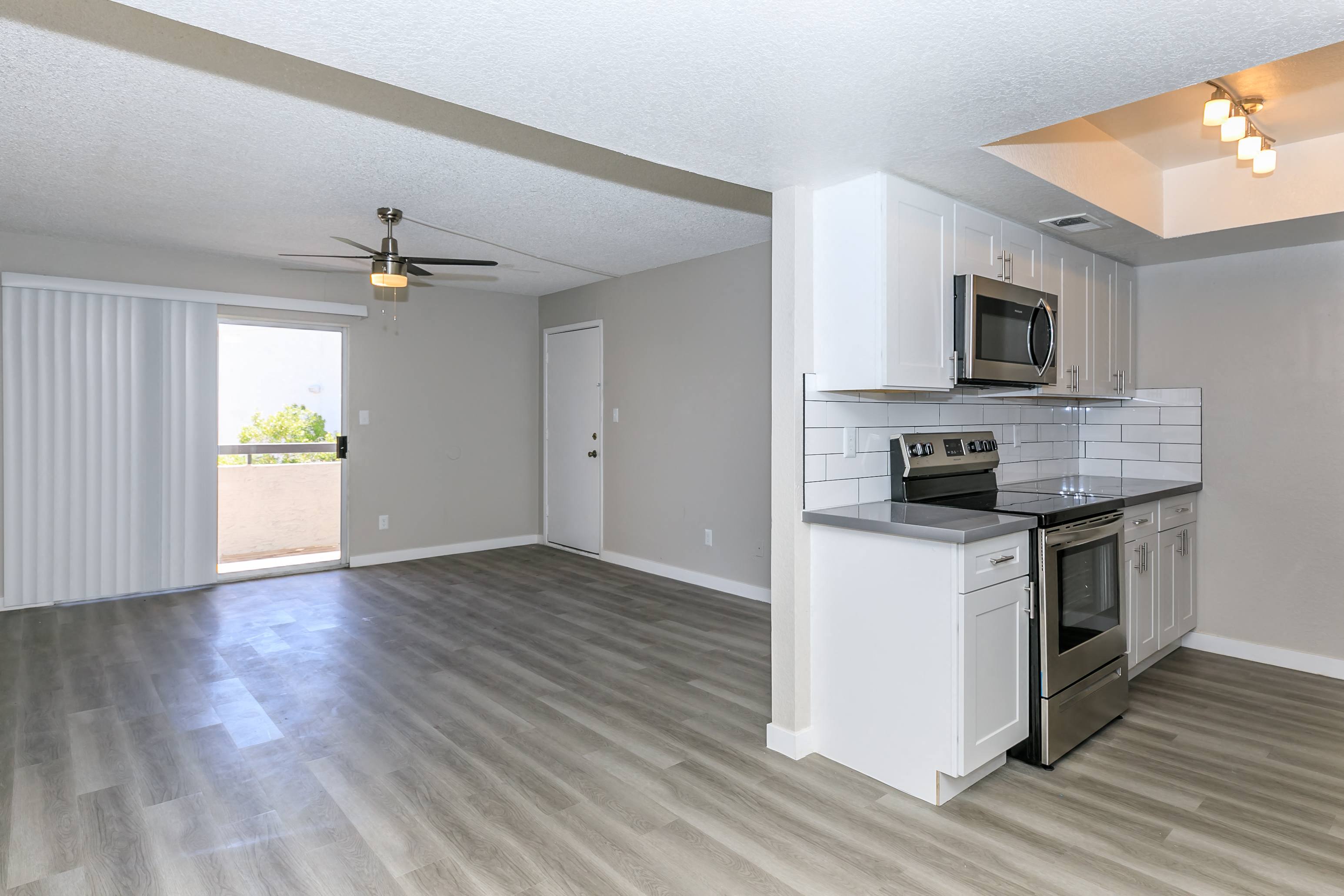 an empty kitchen and living room with a ceiling fan