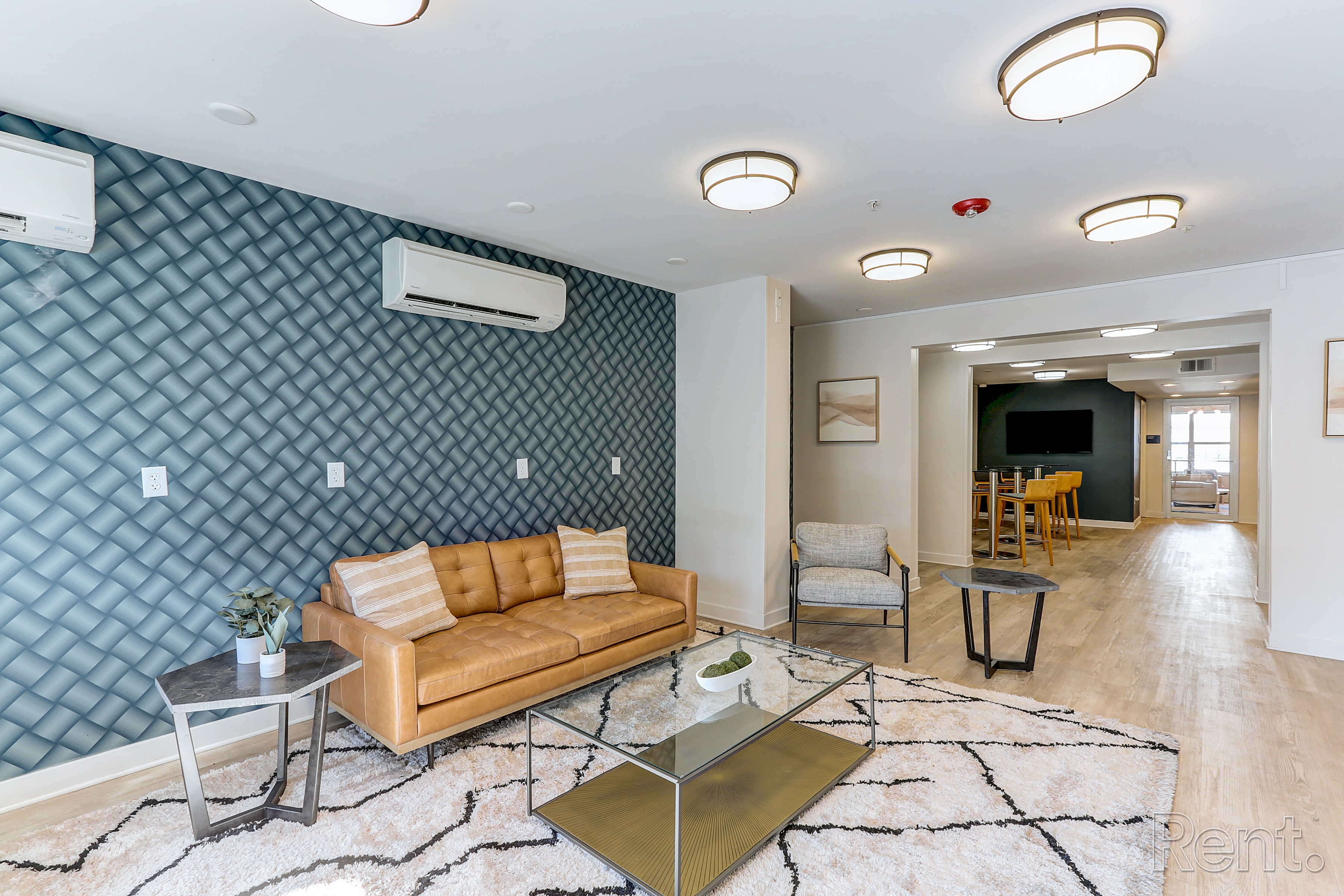 A living room with a blue patterned wall and a tan couch at AVIA North Shore in Jeffersonville, IN