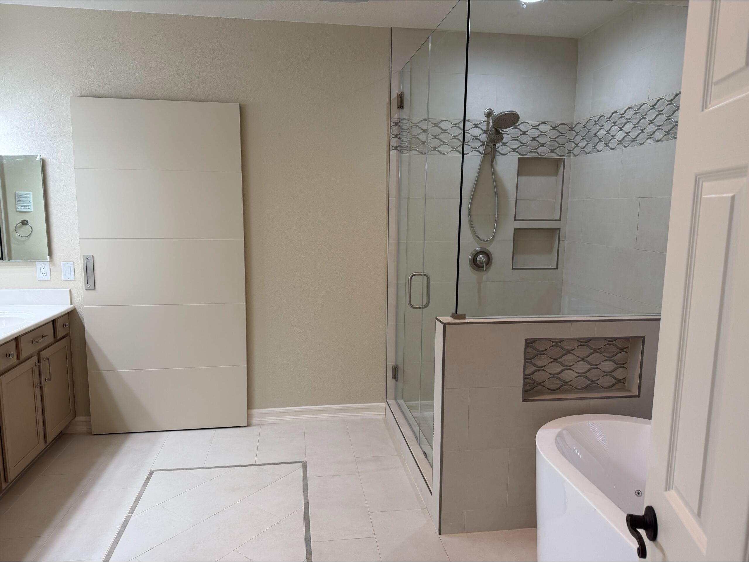 Another Las Vegas bathroom remodel completed by DV2 Pro Remodeling. This primary bathroom features a frameless glass walk-in shower with decorative mosaic tile accents, dual built-in niches for storage, a freestanding soaking tub, and new tile flooring with a custom border detail. We specialize in full bathroom renovations for homeowners across Las Vegas, Henderson, Summerlin, and North Las Vegas. Request a free bathroom remodeling estimate today.