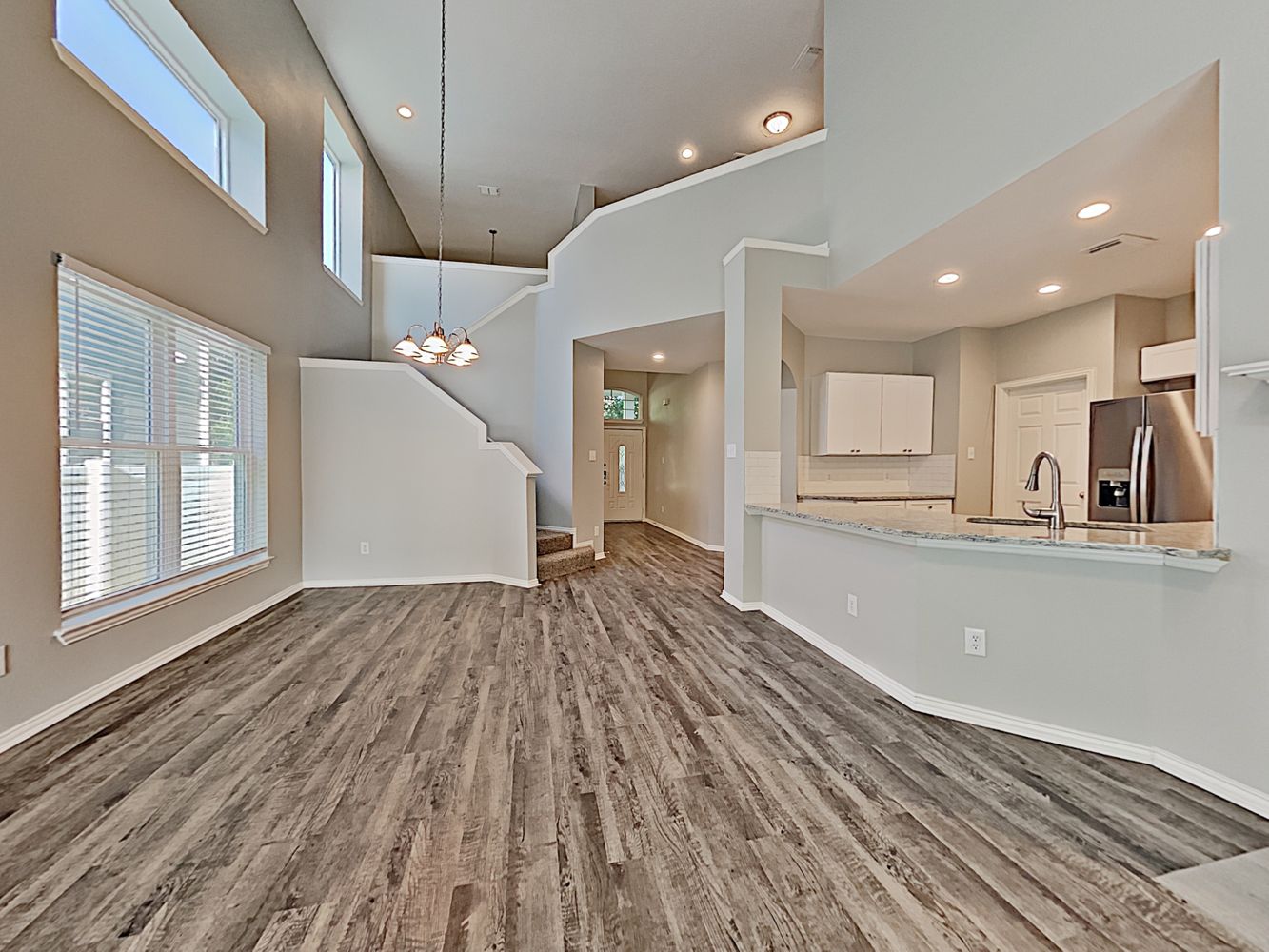 Large family room with luxury vinyl plank flooring and easy access to the kitchen at Invitation Homes Houston.