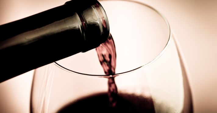 Red wine being poured into a wine glass.
