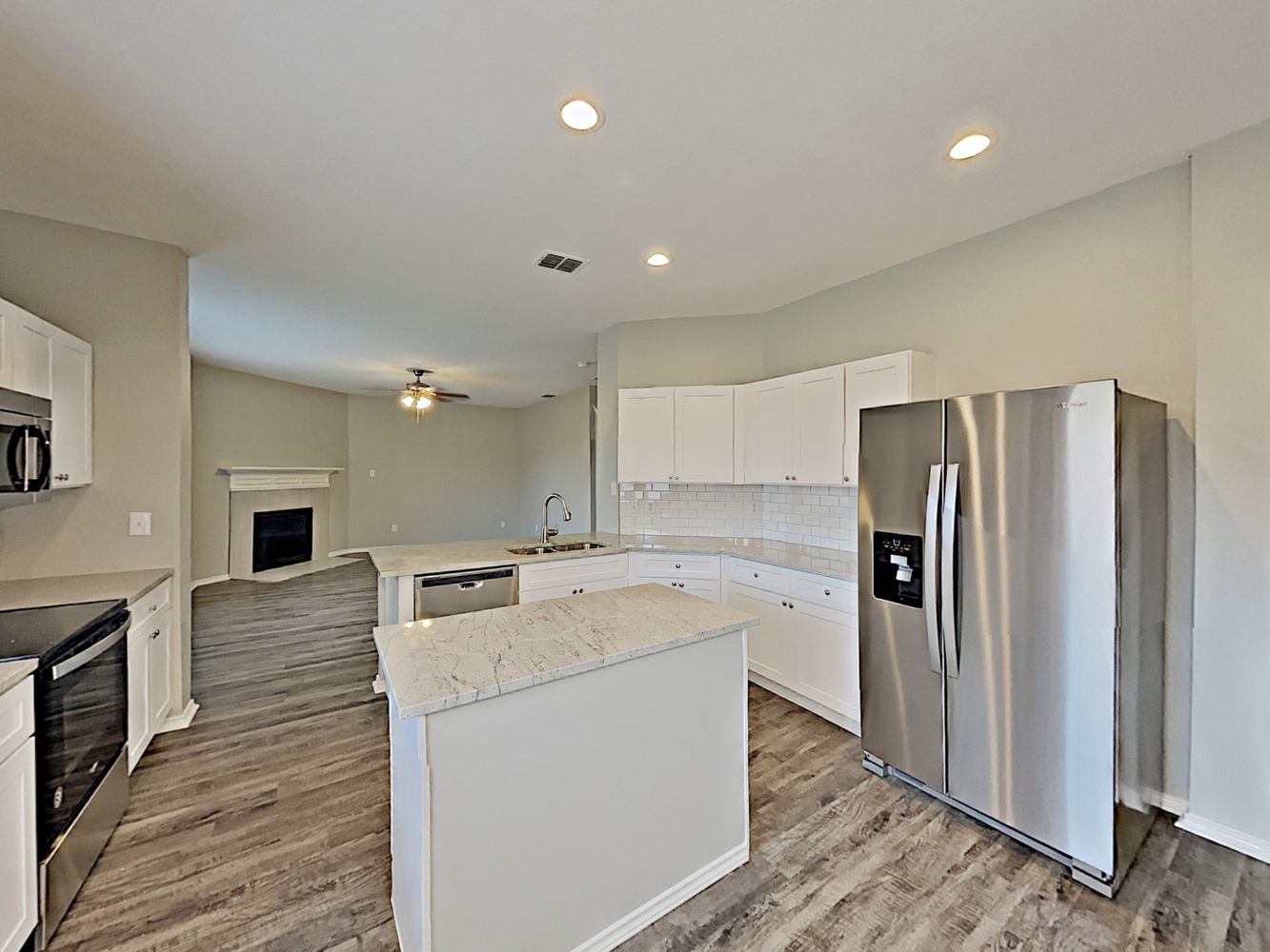 Kitchen with luxury vinyl plank flooring, stainless-steel appliances and an island at Invitation Homes Dallas.