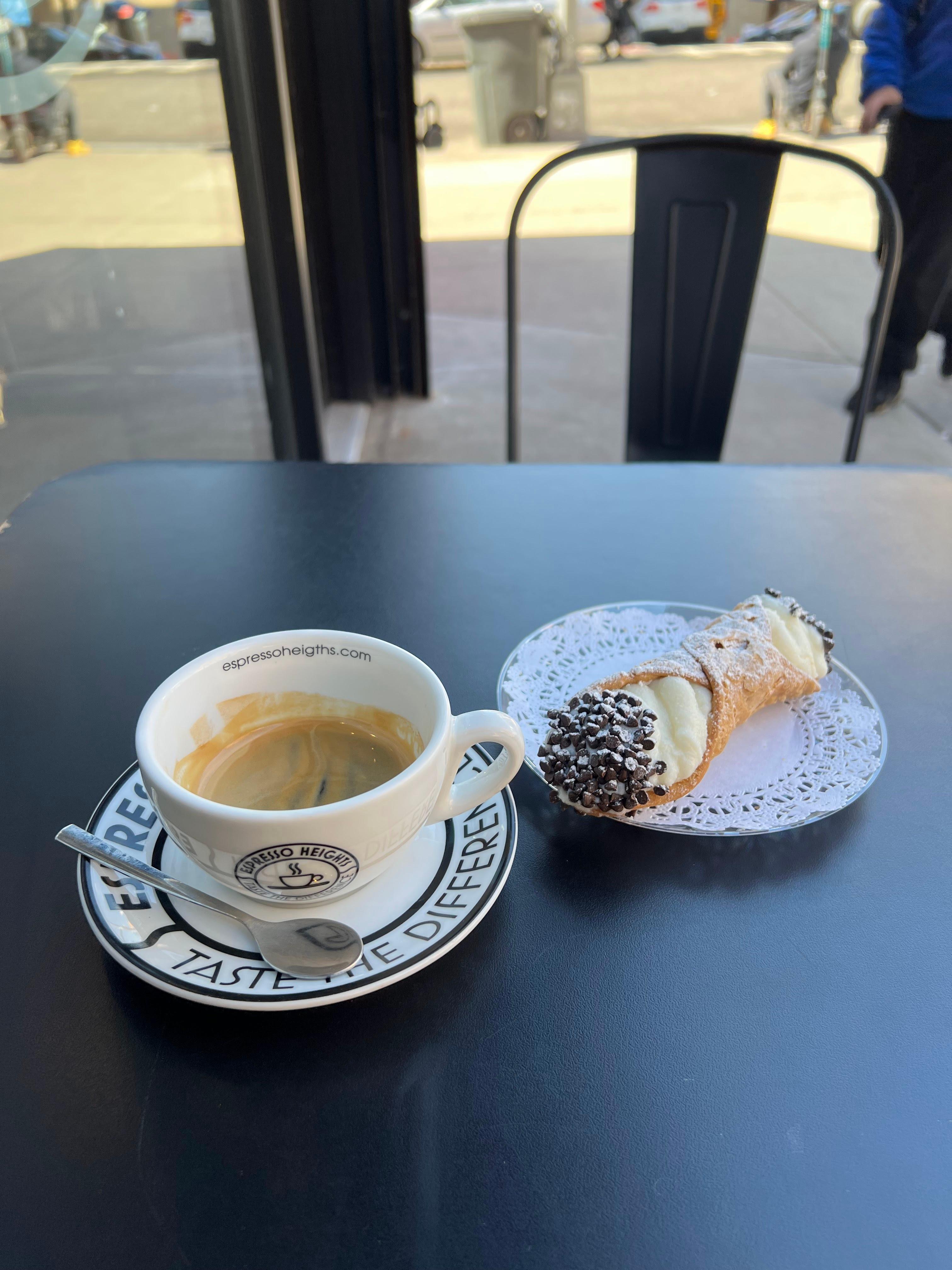 Double espresso served in a cup and a large cannoli