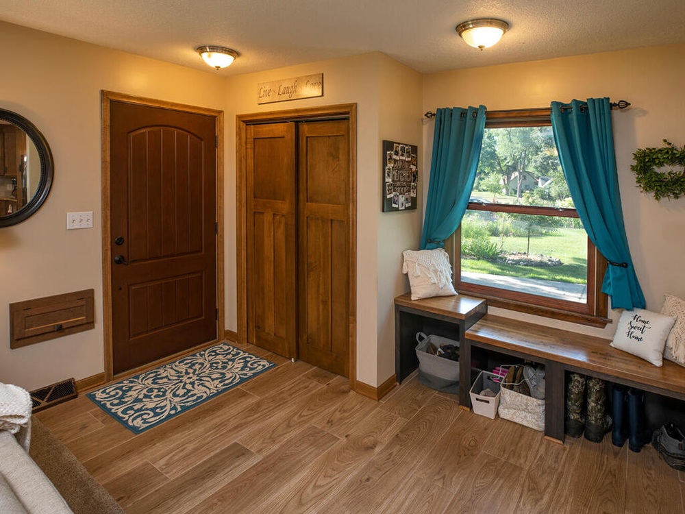 ZimmTown Construction's entryway remodel blends style and function with a modern door, fresh neutral walls, and custom trim. A statement light, durable flooring, and built-in storage create a welcoming, organized space that showcases expert craftsmanship.