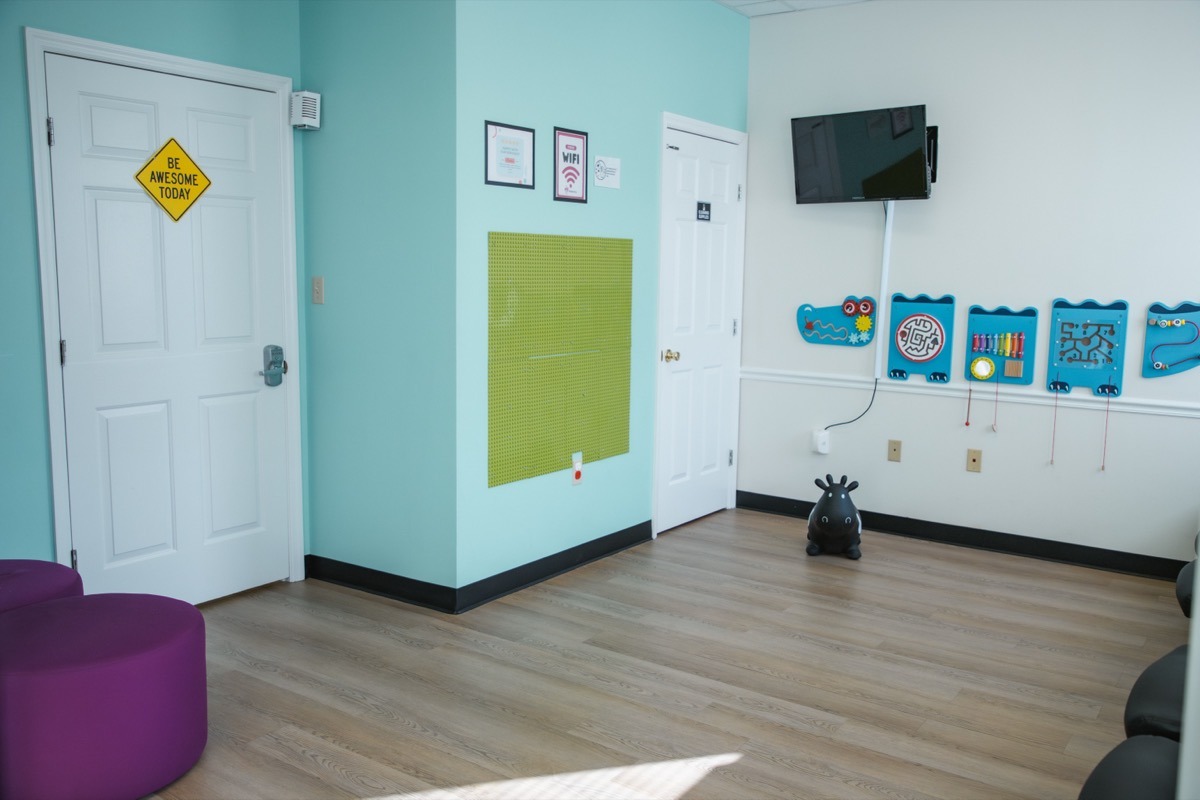 Kid-friendly waiting room at A+ Pediatrics in Irvine, KY, with wall activities, seating, and bright colors.