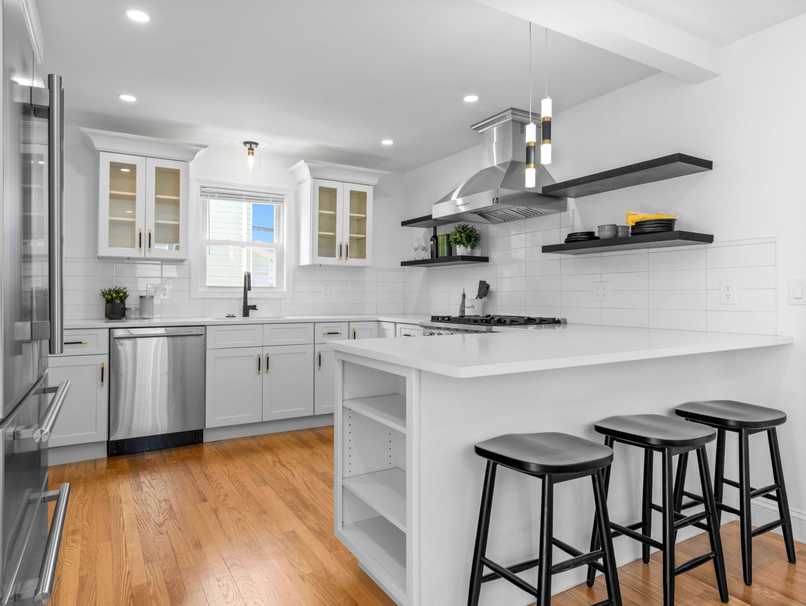 A modern kitchen with white cabinets, stainless steel appliances, and a central island with bar stools.