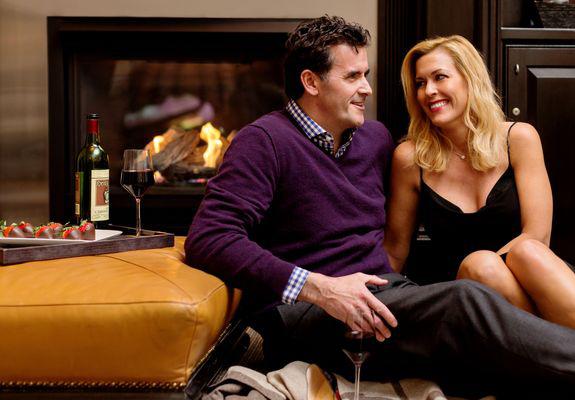 XV Beacon, a luxury Hotel in Boston. Image of couple in front of fireplace with chocolate covered strawberries.