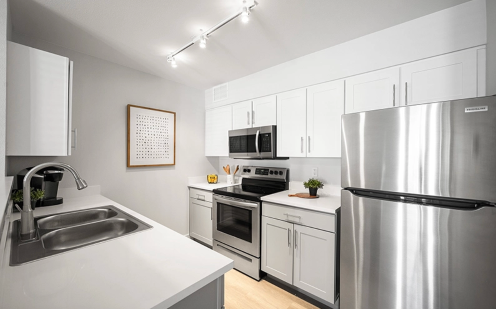 Spacious kitchen with stainless steel appliances, white cabinets, and white quartz countertops.