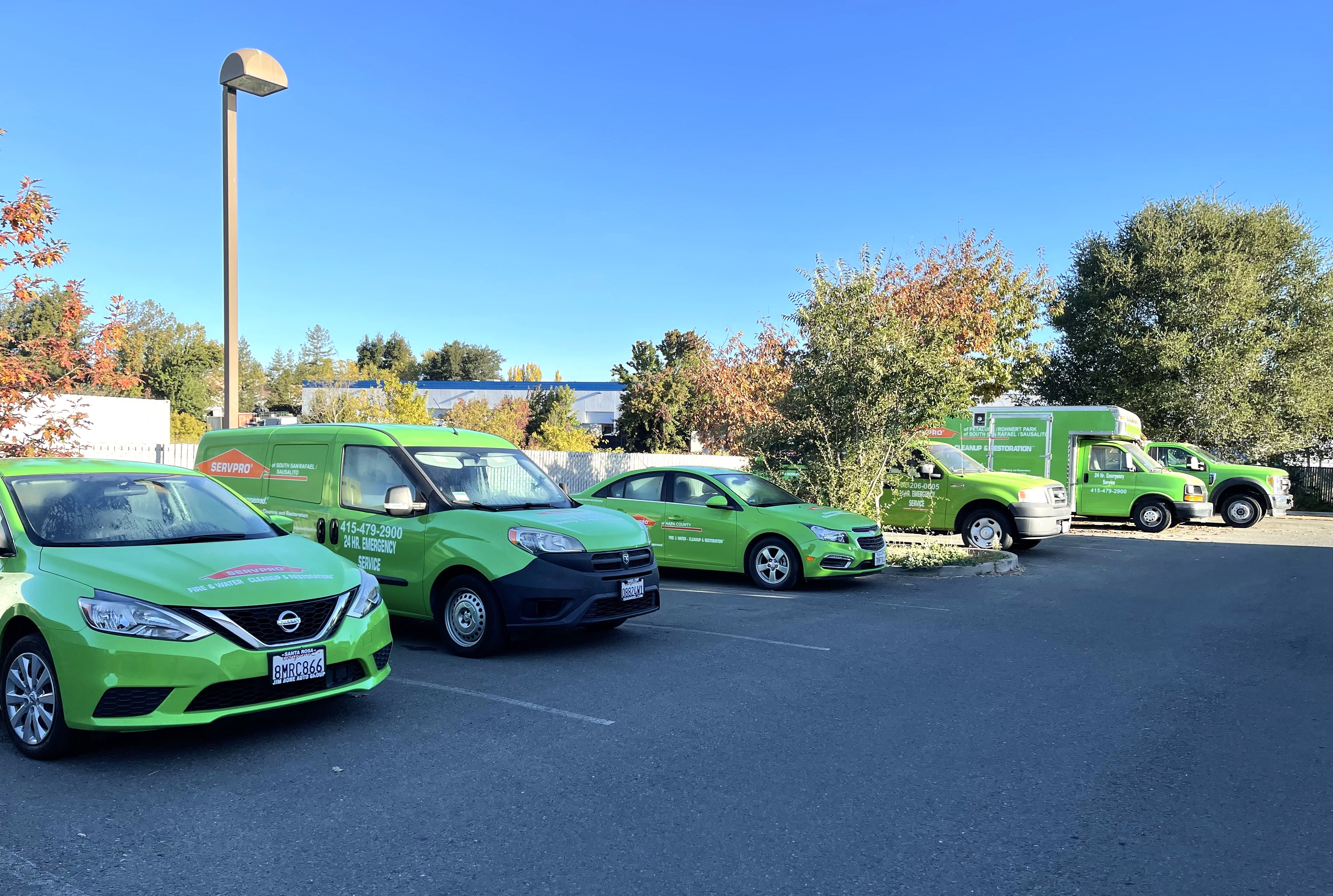 This photo includes six SERVPRO vehicles. This contains two vans, two trucks  and two sedans. All   SERVPRO's vehicles painted green and   have an orange official logo on each side of the vehicles. The vehicles are in the parking lot of 373 Blodgett Street and are parked facing the front entrance of the office building's services.