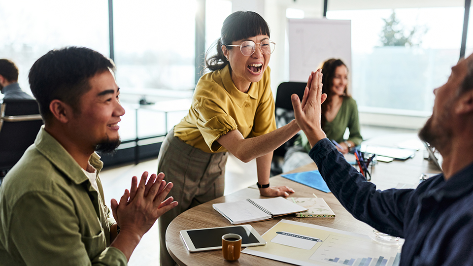 A woman and man high fiving in an office.