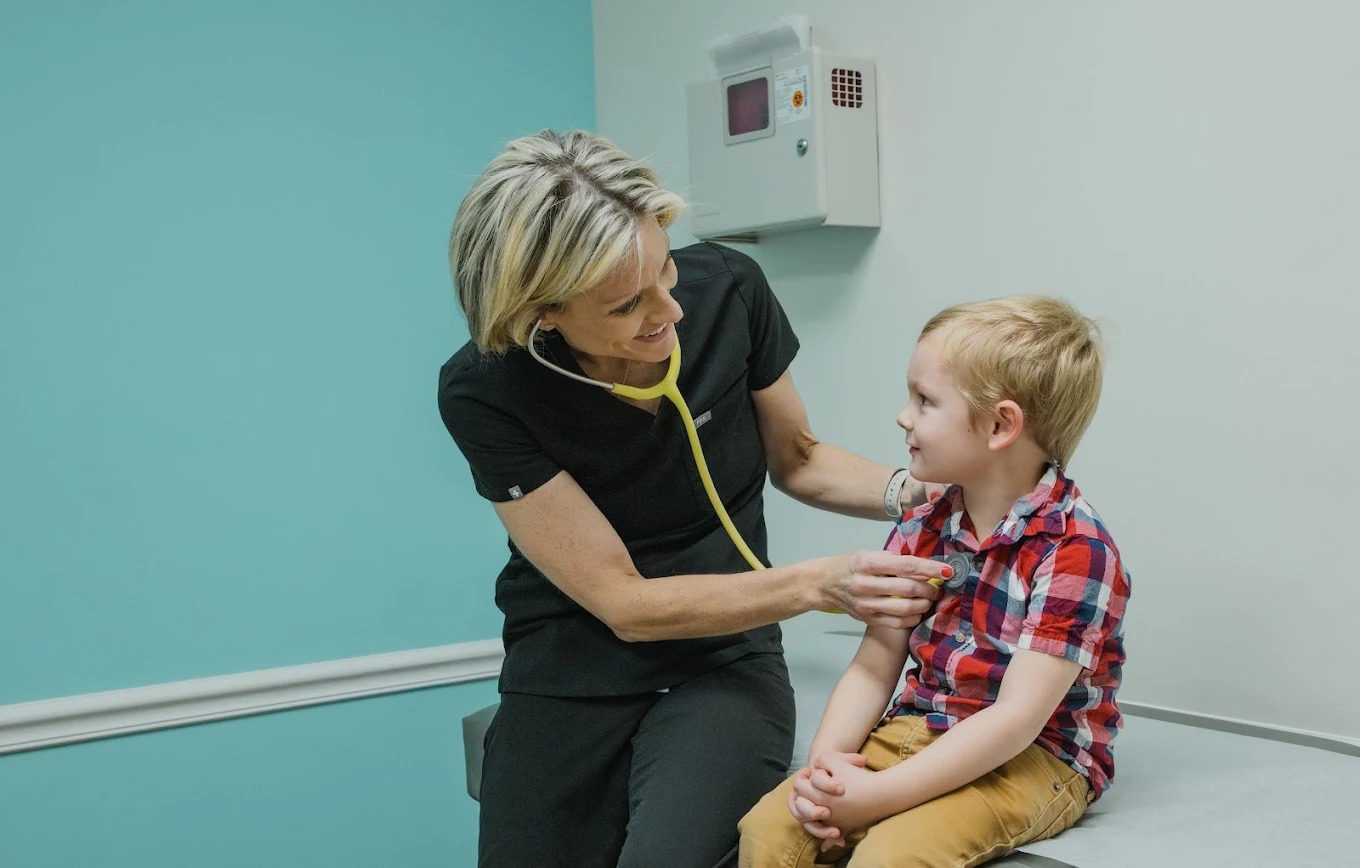 Jennifer Maupin checking a young child with a stethoscope during a pediatric visit at A+ Pediatrics.